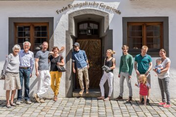 Menschen vor dem Eingang der FeG Augsburg-Mitte im Halbkreis